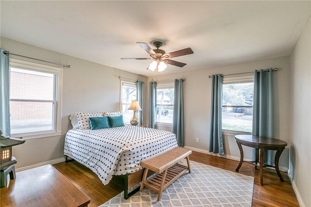 bedroom featuring multiple windows, wood finished floors, and baseboards