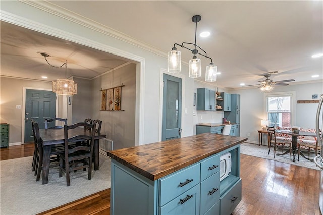 kitchen featuring dark wood-style floors, butcher block counters, white microwave, and blue cabinets