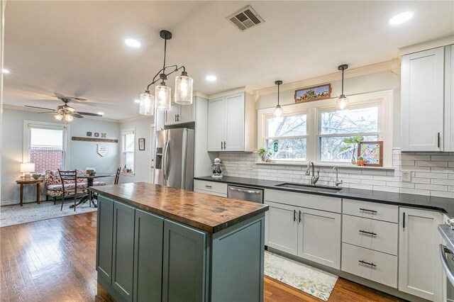 kitchen featuring stainless steel appliances, a sink, visible vents, wooden counters, and dark wood-style floors