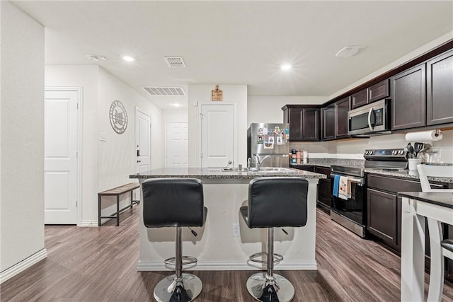 kitchen featuring appliances with stainless steel finishes, visible vents, dark wood finished floors, and a kitchen bar