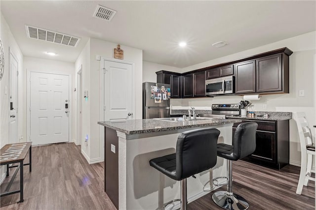 kitchen with stainless steel appliances, stone counters, a sink, and visible vents