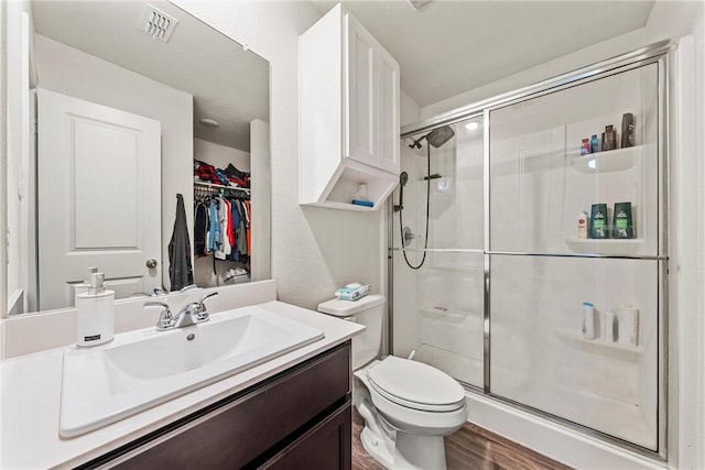 bathroom with toilet, a stall shower, visible vents, and vanity