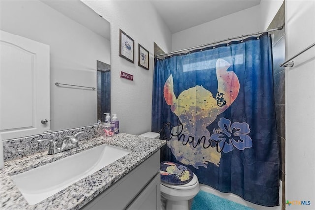 bathroom featuring toilet, vanity, and curtained shower