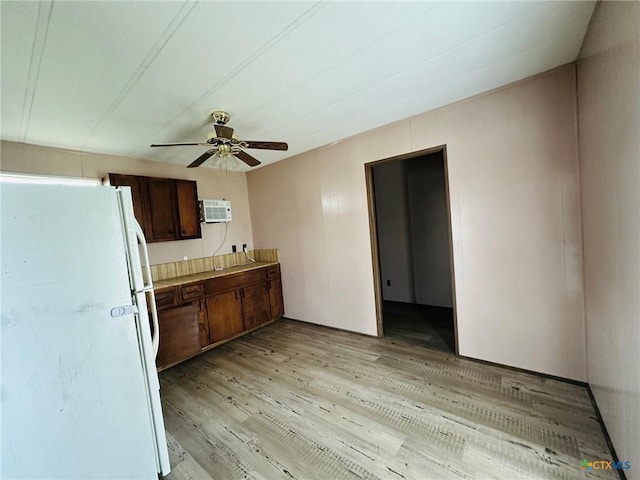 kitchen with dark brown cabinetry, light hardwood / wood-style flooring, an AC wall unit, white fridge, and ceiling fan