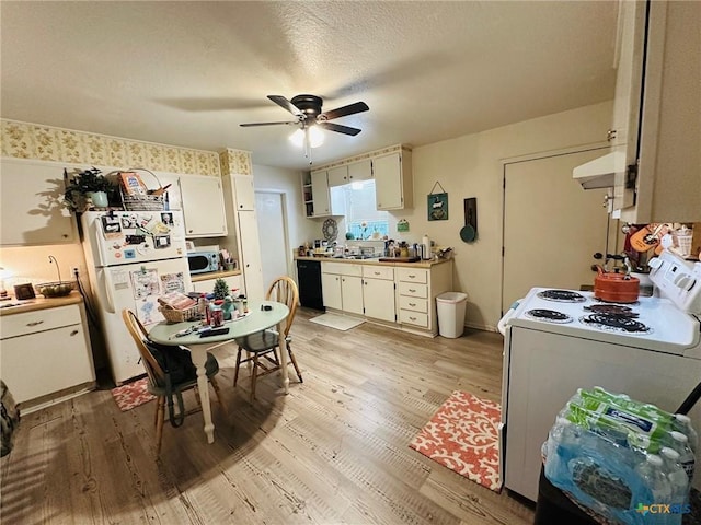 kitchen with light wood-type flooring, a textured ceiling, white cabinets, and white appliances