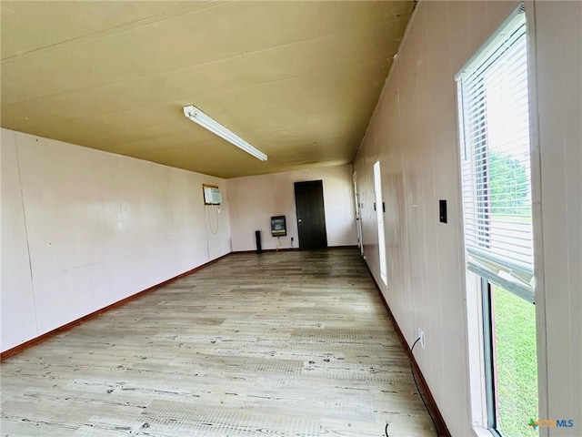 hallway with a wall mounted AC, a healthy amount of sunlight, and light wood-type flooring