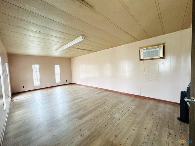 empty room featuring a wall unit AC and light hardwood / wood-style floors