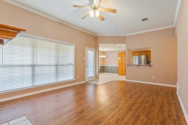 unfurnished room featuring crown molding, wood-type flooring, and ceiling fan with notable chandelier