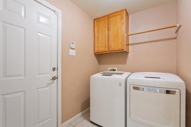 laundry room featuring washer and dryer, light tile patterned floors, and cabinets