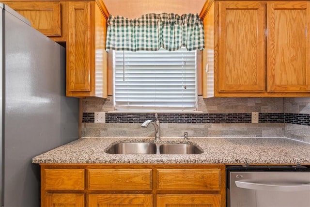 kitchen featuring backsplash, light stone countertops, sink, and appliances with stainless steel finishes