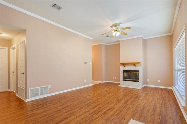 unfurnished living room with a tiled fireplace, a wealth of natural light, hardwood / wood-style floors, and ceiling fan