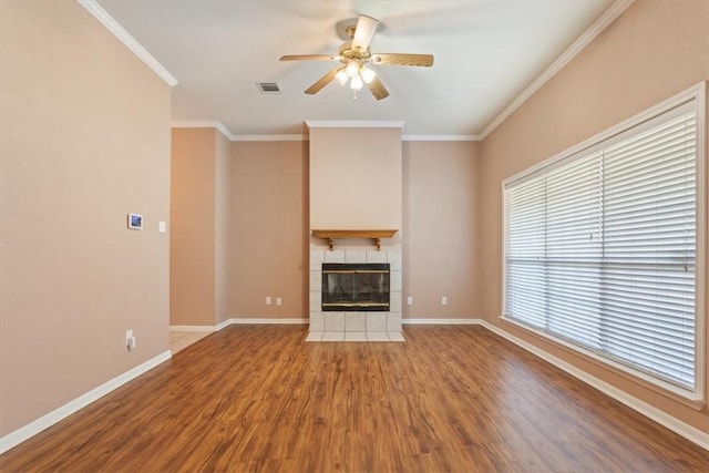 unfurnished living room with hardwood / wood-style flooring, a tiled fireplace, a wealth of natural light, and ceiling fan