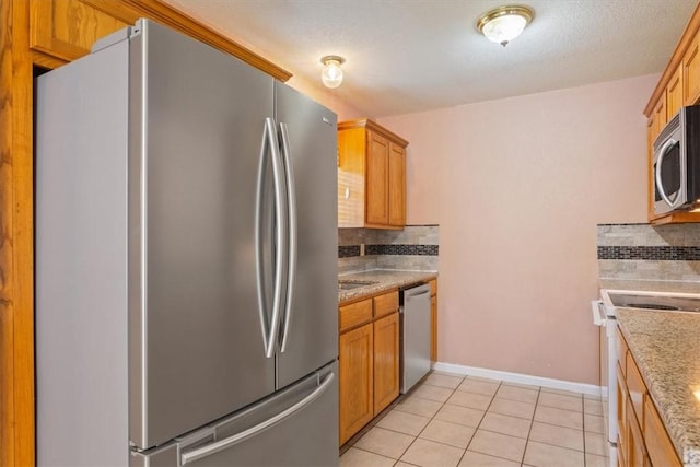 kitchen with decorative backsplash, light tile patterned floors, and stainless steel appliances