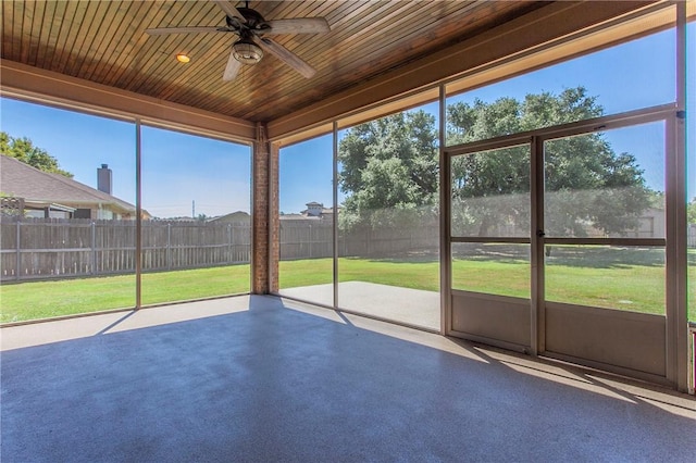 unfurnished sunroom featuring ceiling fan, a wealth of natural light, and wood ceiling