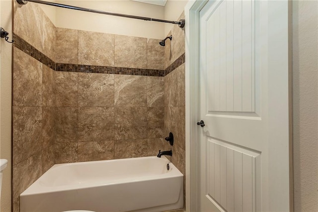 bathroom featuring tiled shower / bath combo and toilet