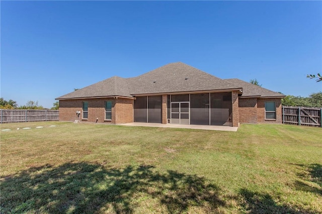 rear view of house featuring a sunroom and a lawn