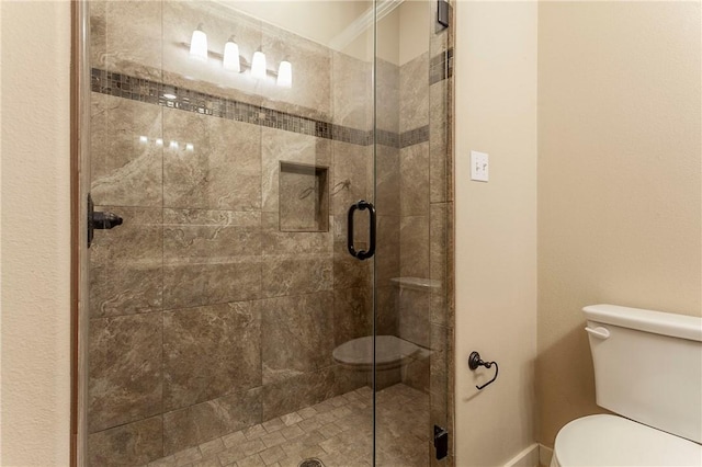 bathroom featuring toilet, a shower with shower door, and crown molding