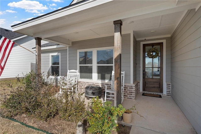 doorway to property with covered porch and brick siding