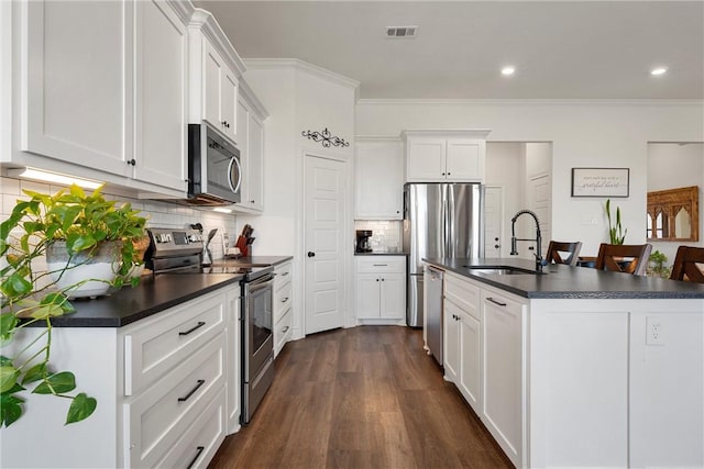 kitchen featuring visible vents, a sink, dark countertops, dark wood-style floors, and appliances with stainless steel finishes