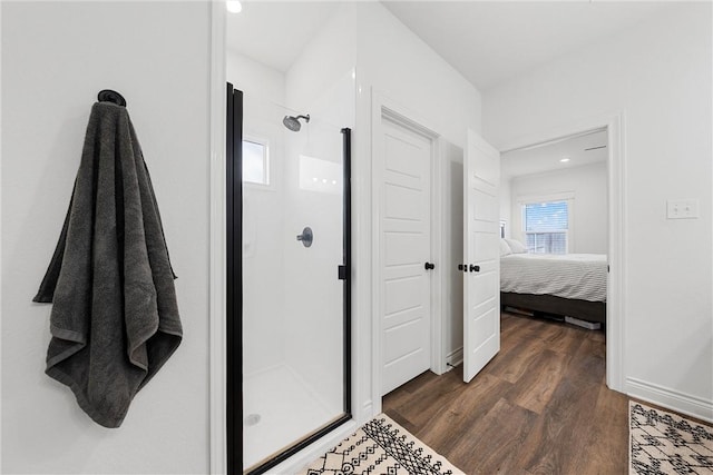 bathroom featuring baseboards, wood finished floors, ensuite bath, and a stall shower