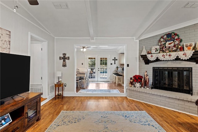 living room featuring ceiling fan, light hardwood / wood-style floors, a fireplace, and french doors