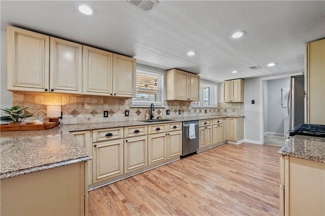 kitchen featuring light stone countertops, light wood-type flooring, tasteful backsplash, sink, and dishwasher