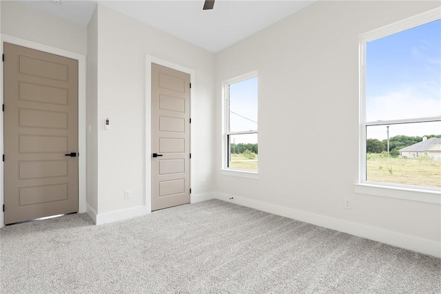 unfurnished bedroom featuring multiple windows, light carpet, and ceiling fan