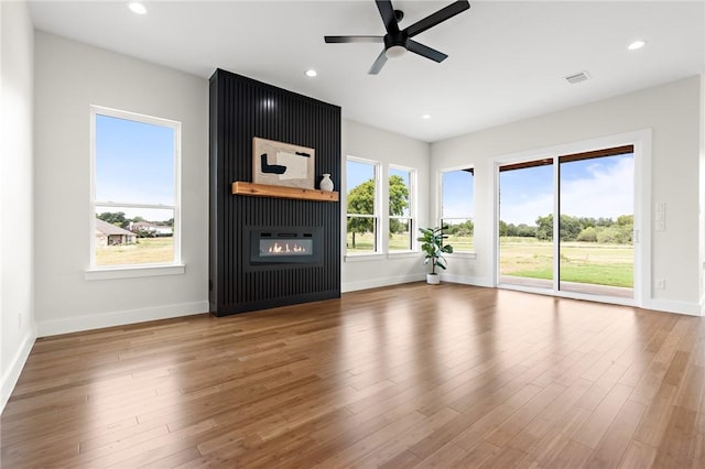 unfurnished living room with a fireplace, wood-type flooring, and ceiling fan