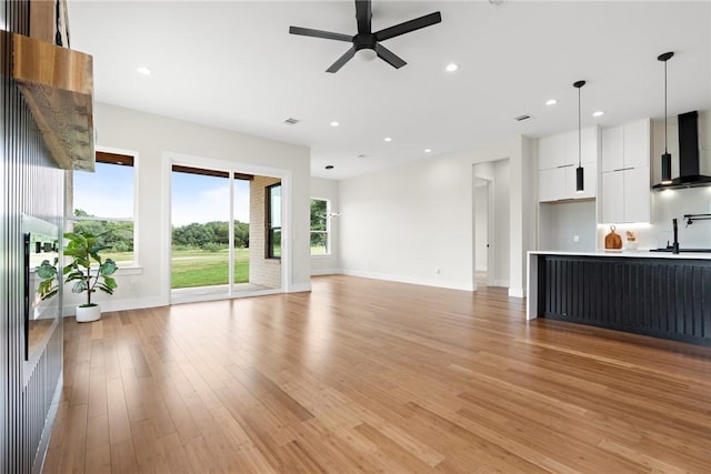 unfurnished living room with ceiling fan, light hardwood / wood-style flooring, and sink