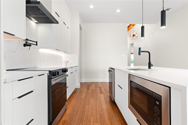 kitchen with pendant lighting, white cabinets, extractor fan, and appliances with stainless steel finishes