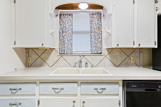 kitchen with decorative backsplash, white cabinetry, sink, and black dishwasher