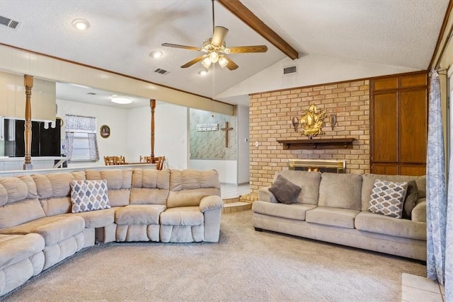 carpeted living room with ceiling fan, lofted ceiling with beams, a textured ceiling, and a brick fireplace