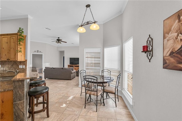 dining space featuring ceiling fan, sink, and ornamental molding