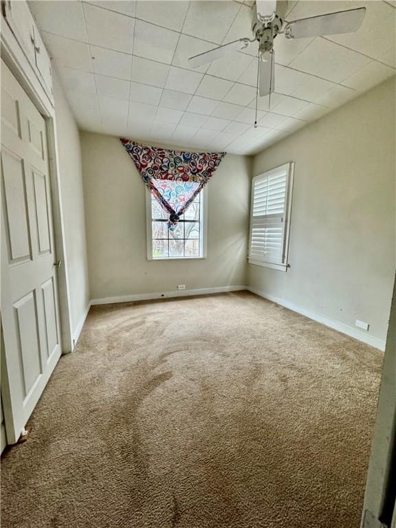 empty room with a ceiling fan, carpet flooring, and baseboards