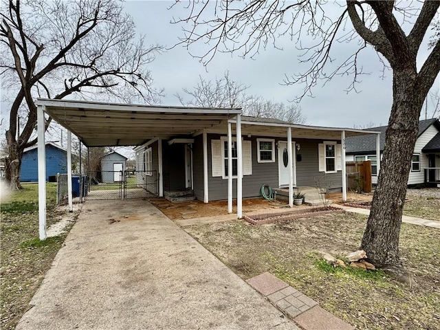 view of front of house with an attached carport, concrete driveway, fence, and a gate