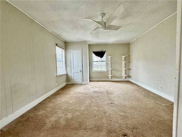 carpeted empty room with ornamental molding, ceiling fan, a textured ceiling, and baseboards