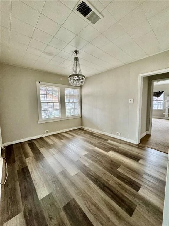 unfurnished dining area with an inviting chandelier, baseboards, visible vents, and dark wood-type flooring