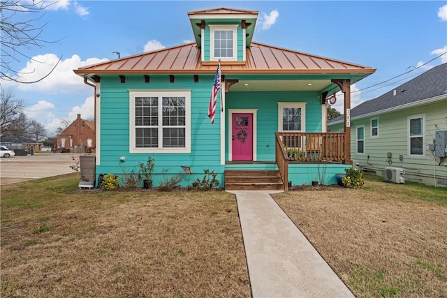 bungalow with covered porch, a front lawn, and central air condition unit