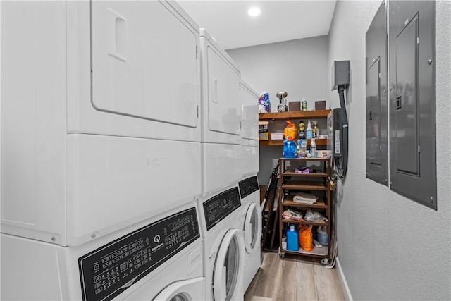 laundry area with stacked washer and clothes dryer, electric panel, light hardwood / wood-style floors, and washer and dryer