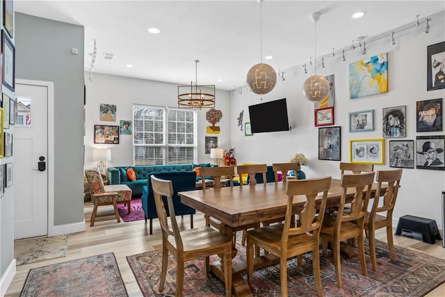 dining space featuring track lighting, a chandelier, and light wood-type flooring