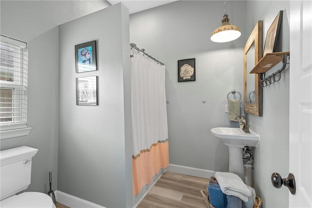 bathroom with curtained shower, wood-type flooring, and toilet