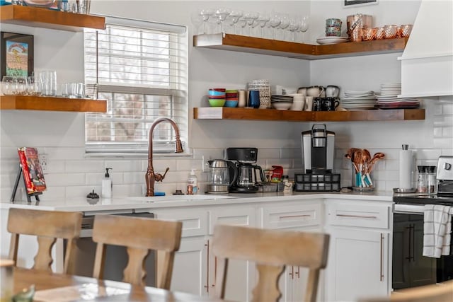 kitchen with decorative backsplash, sink, electric range oven, and white cabinets