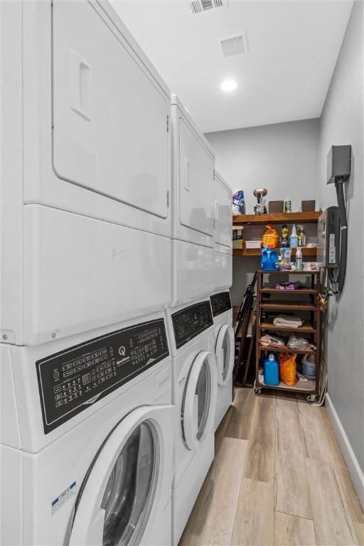 clothes washing area featuring washer and dryer, stacked washer / drying machine, and light wood-type flooring