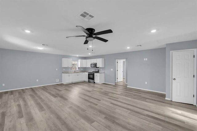 unfurnished living room featuring ceiling fan, sink, and light wood-type flooring