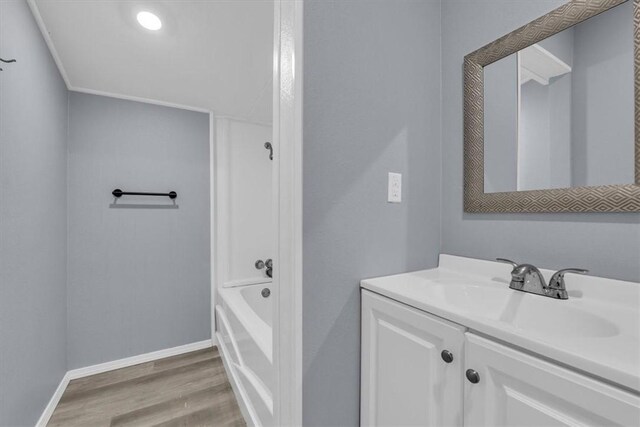 bathroom with a tub to relax in, vanity, and hardwood / wood-style floors