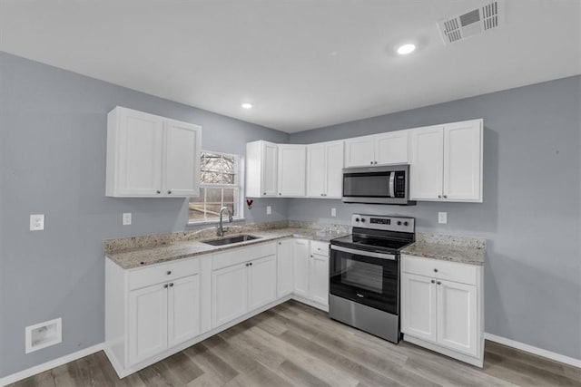 kitchen featuring sink, light wood-type flooring, white cabinets, and appliances with stainless steel finishes