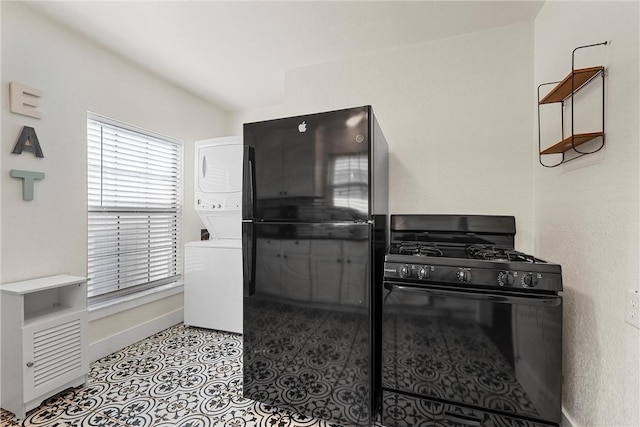 kitchen with baseboards, stacked washing maching and dryer, and black appliances