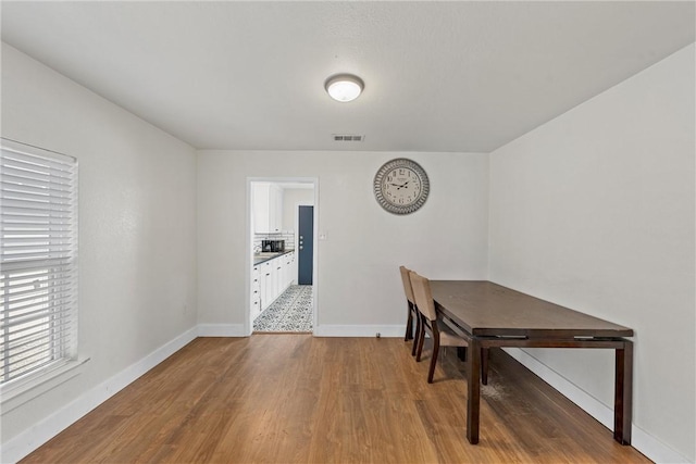 dining room featuring wood finished floors, visible vents, and baseboards