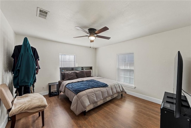 bedroom featuring a textured ceiling, wood finished floors, visible vents, and baseboards