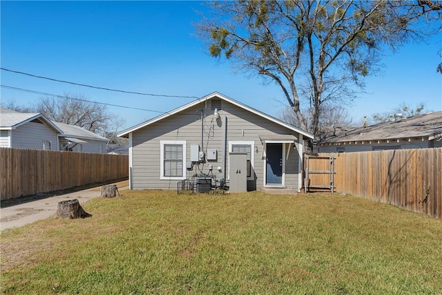 back of house with a fenced backyard and a yard